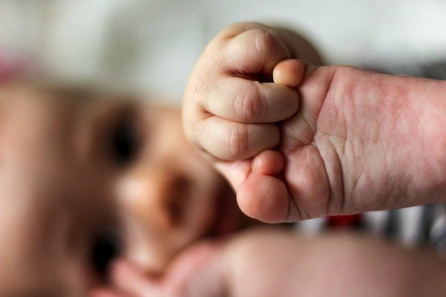 Baby holding feet with feet in foreground.