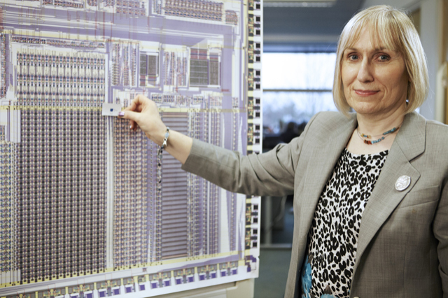 Sophie Wilson holding a chip up against a giant enlarged image