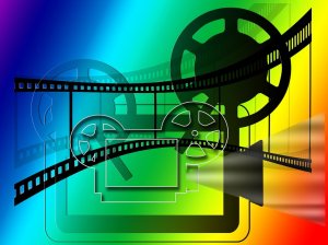 Film projector with film strip on a coloured rainbow background, from Pixabay