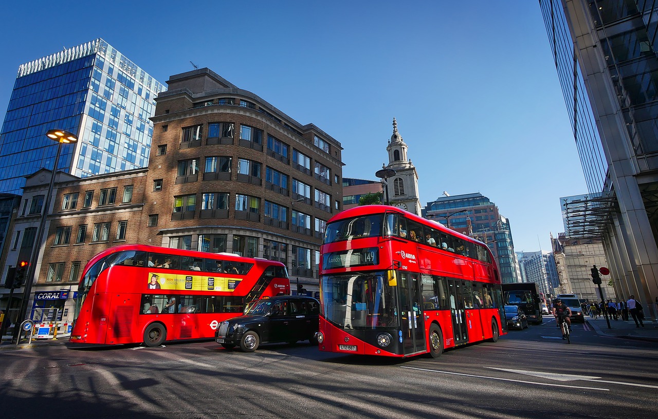 Street in London with two red buses going in opposite directions.
