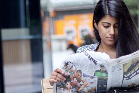 Woman of asian descent reading a newspaper