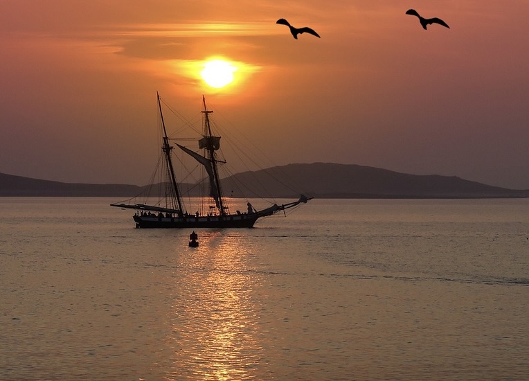 Sunset over the Scilly Isles with a sailing boat in the foreground