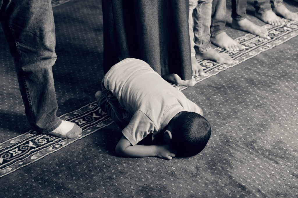 A child in prayer bowing low to God in the direction of Mecca