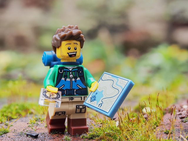A lego minifigure hiking with map and compass
