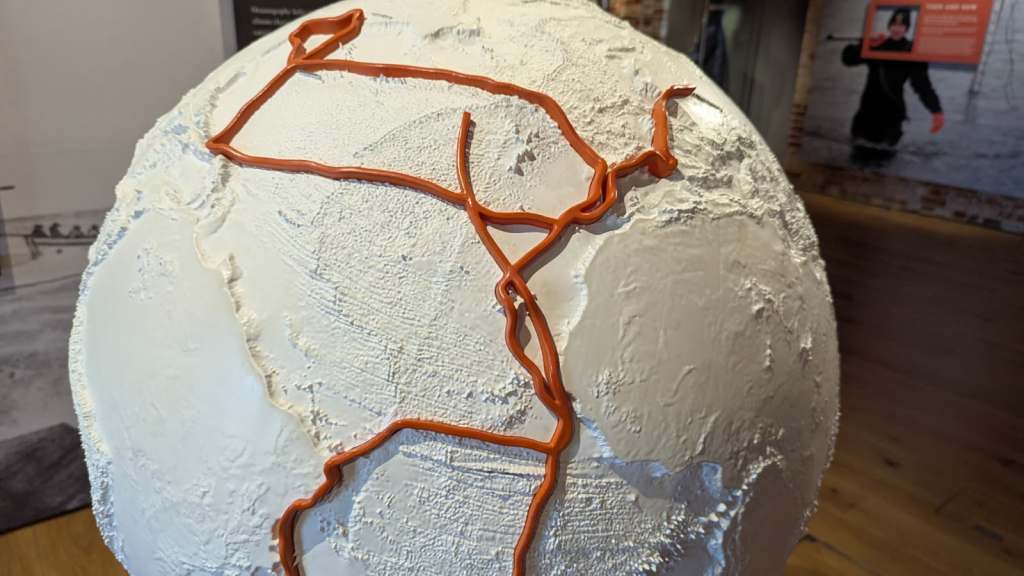 A globe (North Atlantic visible) showing ocean depth information, with the path of HMS Challenger shown in red.