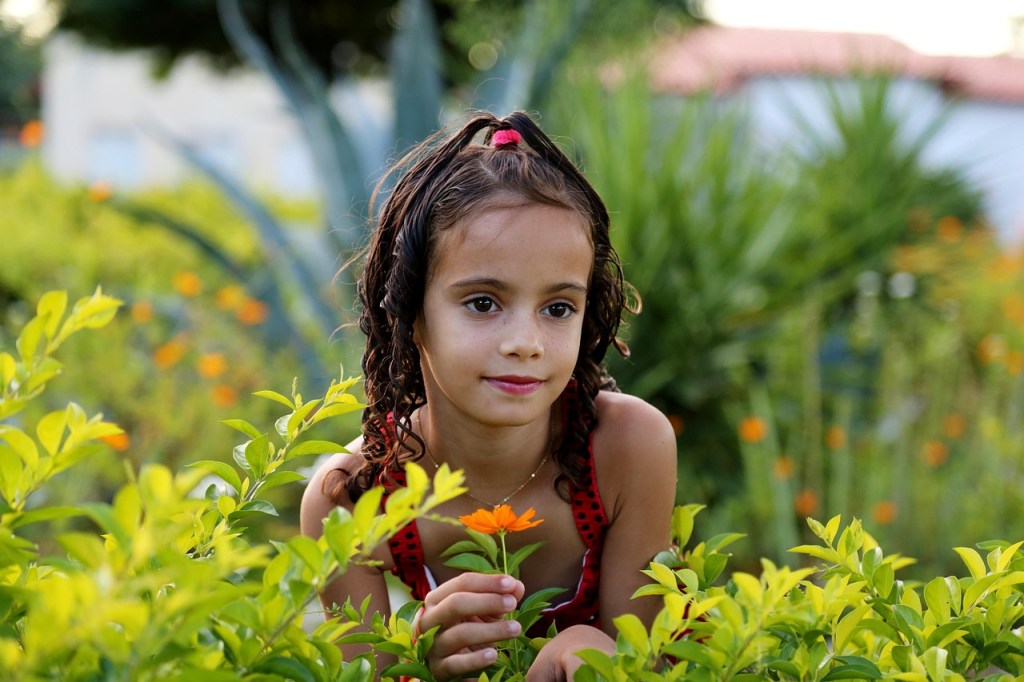 A girl in a garden holding an orange flower