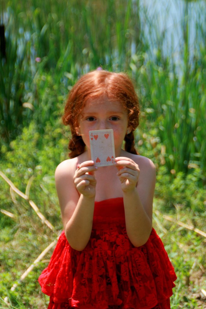 A girl holding a 4 of Hearts